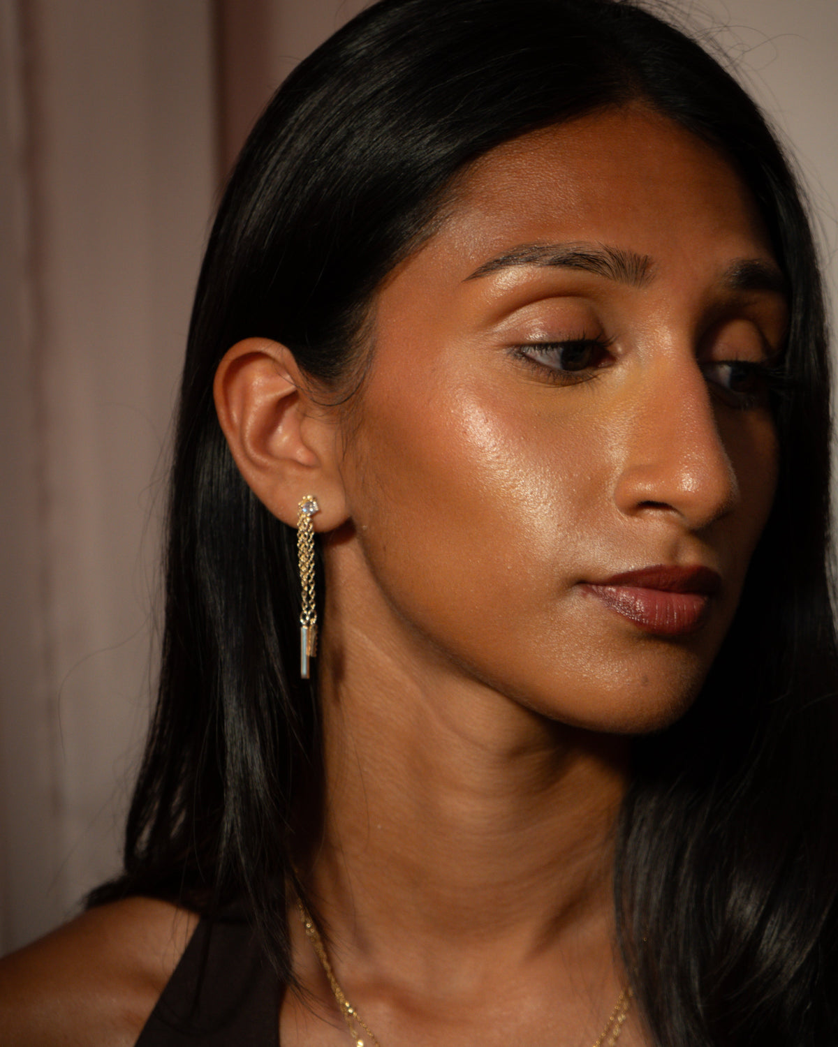 The Thread gold chain drop earring worn on the ear, round stone stud with two chains ending in pavé and plain bars