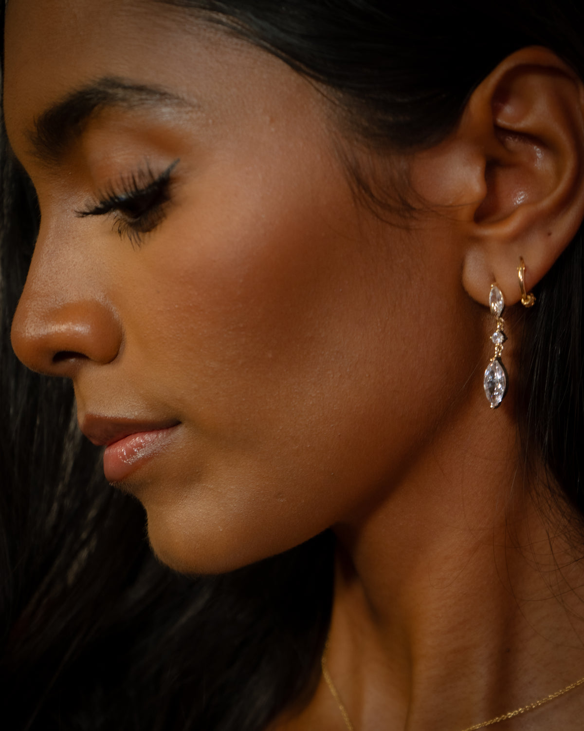 The Gaze gold marquise drop earring worn on the ear, three clear stones on fine gold links